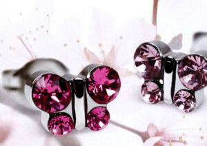 Ein Paar gl&auml;nzender silberner Ohrringe in Form eines Schmetterlings mit rosafarbenen Edelsteinen vor einem zarten Hintergrund mit hellrosa Kirschbl&uuml;ten.