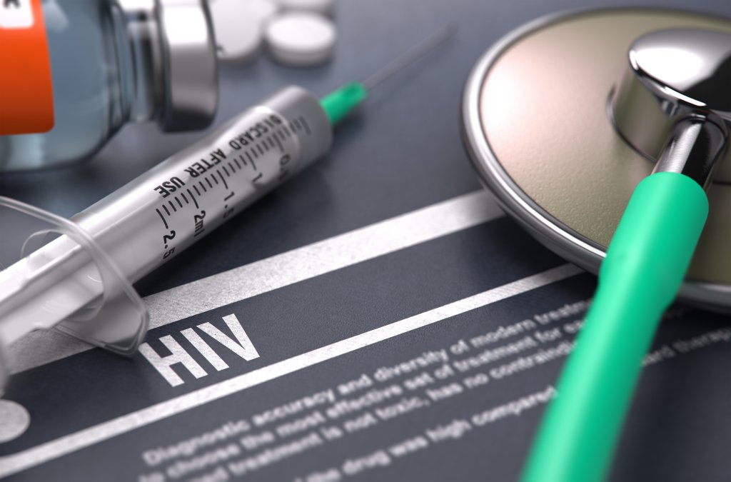 Eine Spritze, ein Stethoskop und ein Pillenfl&auml;schchen stehen auf einer Fl&auml;che, auf der das Wort HIV in fetten Buchstaben steht und die medizinische Behandlung oder Diagnose von HIV symbolisiert.