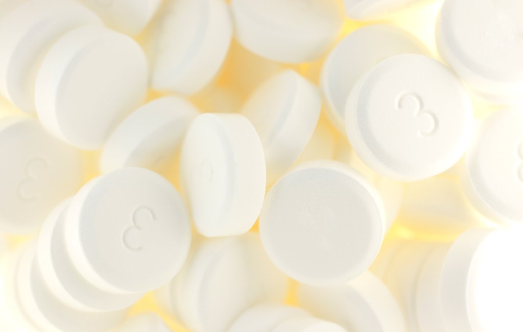 Nahaufnahme vieler runder, wei&szlig;er Sch&uuml;ssler-Salz-Tabletten mit der auf einigen von ihnen aufgedruckten Zahl 3, die in einem verstreuten Stapel angeordnet sind.