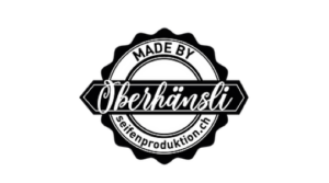 Ein schwarz-weisses, kreisf&ouml;rmiges Logo mit der Aufschrift MADE BY Oberh&auml;nsli unterstreicht die nachhaltigen Werte. Am unteren Rand steht seifenproduktion.ch.