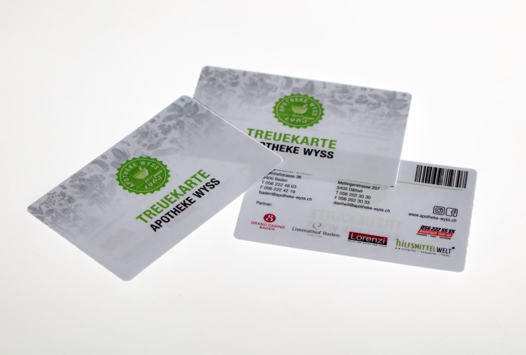 Abgebildet sind zwei Apothekentreuekarten mit der Aufschrift Wyss Treuekarte APOTHEKE WYSS; eine Karte zeigt die Vorderseite mit gr&uuml;nem Text und einem Blattmotiv, die andere die R&uuml;ckseite mit Kontaktinformationen und Partnerlogos.