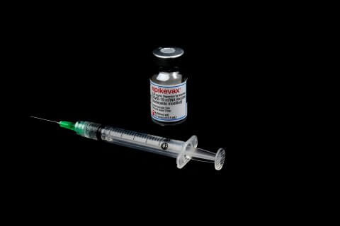 Ein Fl&auml;schchen mit der Aufschrift Spikevax und eine gef&uuml;llte Spritze mit einer Nadel sind auf einem schwarzen Hintergrund platziert, der Impfoptionen f&uuml;r den Herbst 2023 hervorhebt.