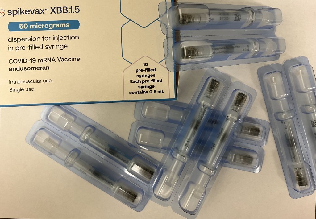 Eine Schachtel mit der Aufschrift spikevax XBB.1.5 COVID-19 mRNA Vaccine ist mit Plastikschalen abgebildet, die vorgef&uuml;llte Spritzen f&uuml;r die intramuskul&auml;re Anwendung enthalten und eine der f&uuml;r Herbst 2023 verf&uuml;gbaren Impfoptionen mit 50 Mikrogramm pro Dosis hervorheben.