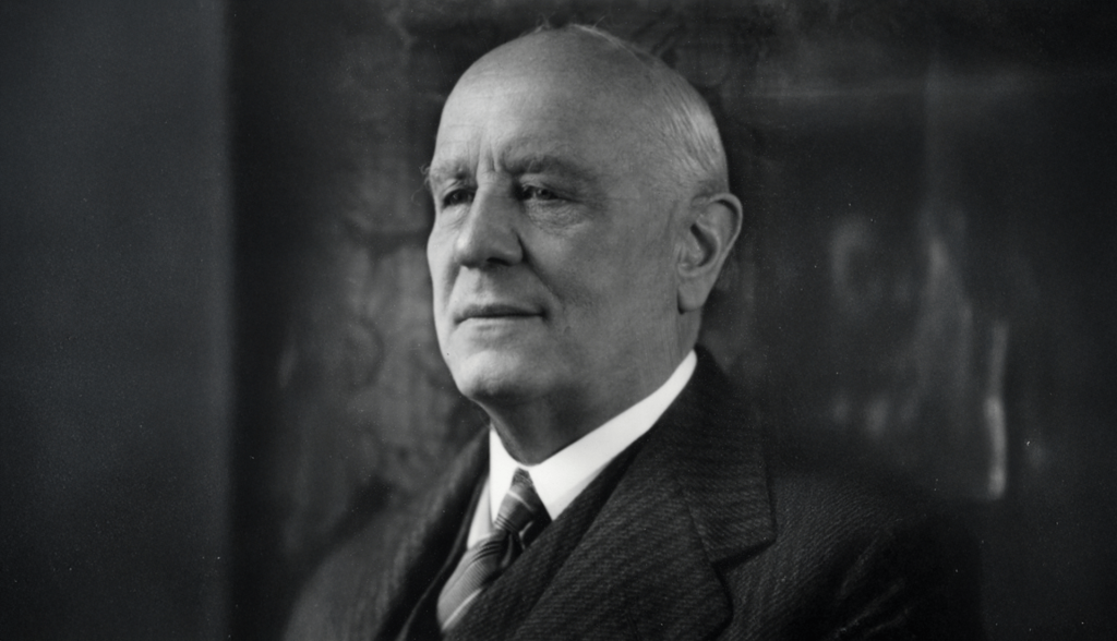 Ein &auml;lterer Mann in Anzug und Krawatte posiert f&uuml;r ein formelles Schwarz-Wei&szlig;-Portr&auml;t. Er blickt leicht nach links und l&auml;chelt sanft, als w&uuml;rde er dar&uuml;ber nachdenken, wieviel angereicherte Lebensmittel wirklich gesund sind. Der Hintergrund ist dunkel und unscharf.